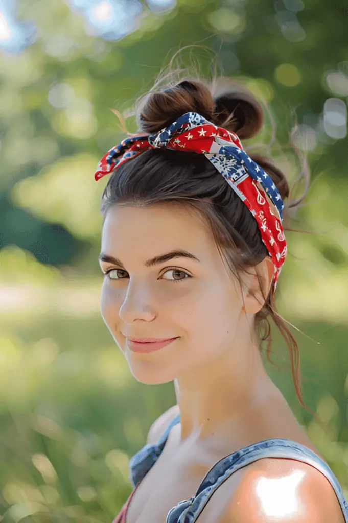 A woman with a high ponytail wrapped with a patriotic bandana, wearing a casual summer outfit, in a sunny park setting during a 4th of July picnic.