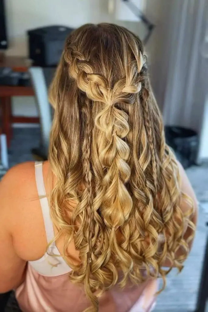 A romantic boho-style half-up half-down hairstyle featuring soft waves and a loose, textured braid, perfect for weddings and festivals.