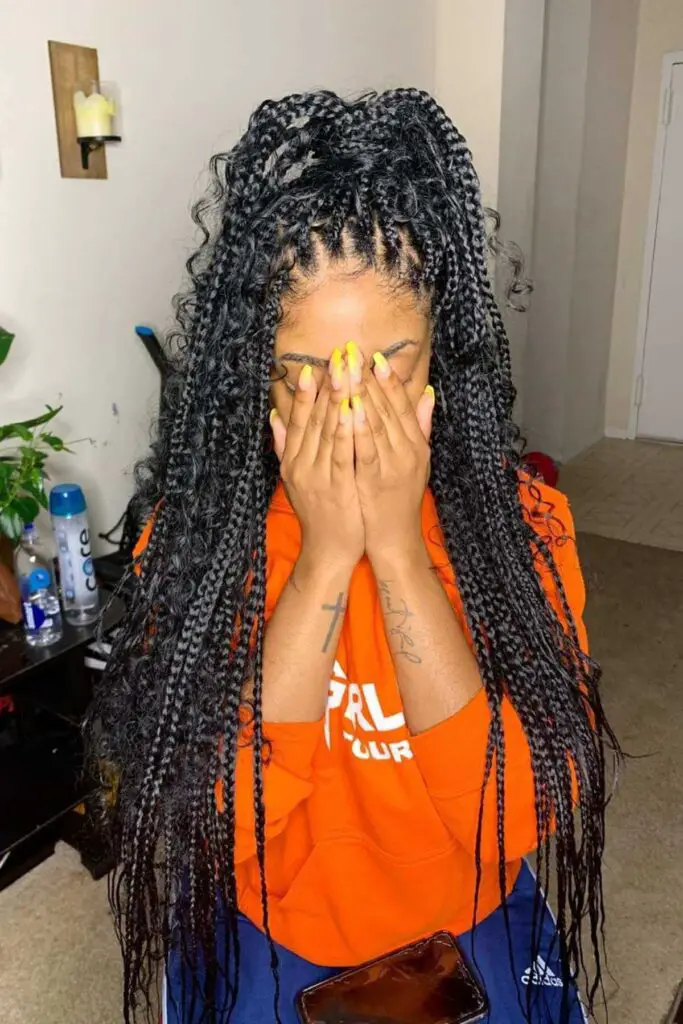 A stylish half-up half-down boho box braids hairstyle with long, curly ends, adding a chic and trendy look for Black women.