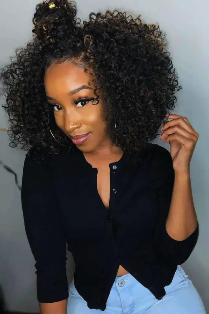 A voluminous half-up curly afro bun with natural, defined curls, perfect for an effortless and bold natural hair look.