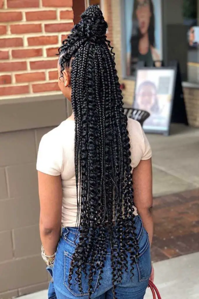 Stunning half-up jumbo box braids with bouncy curly ends, blending structure with a touch of playful elegance.